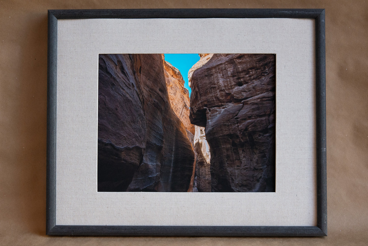 Upward view of the Al Siq Canyon in Jordan. Surrounded by striated red rock. 11x14 framed. Matting is tan with a grey frame.