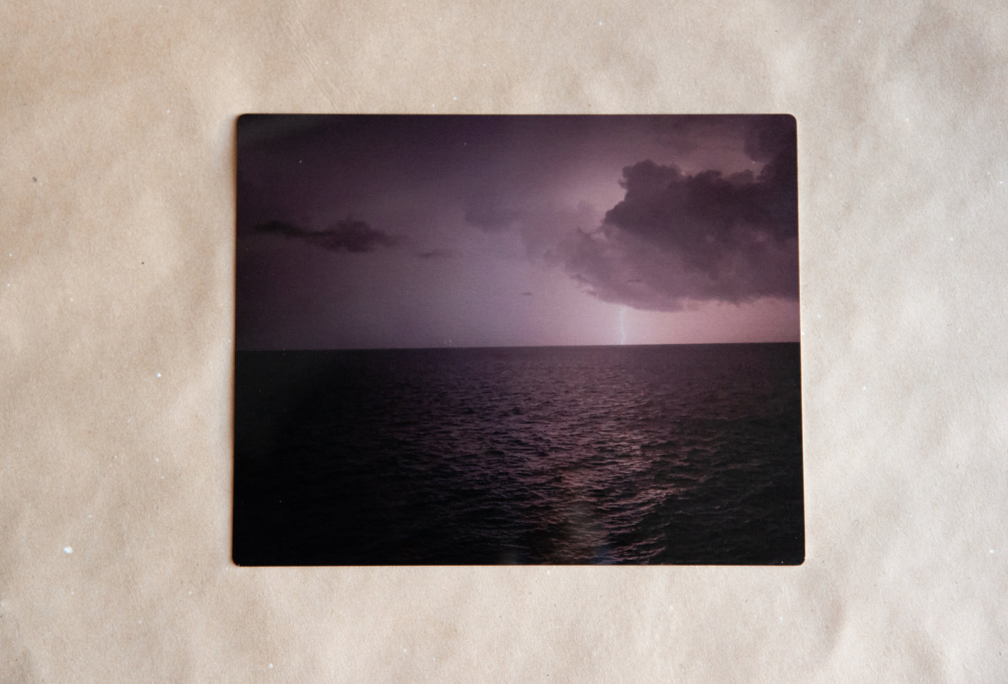 Metal print of a lightning strike over the Atlantic Ocean in black and white. Print on a craft paper background.