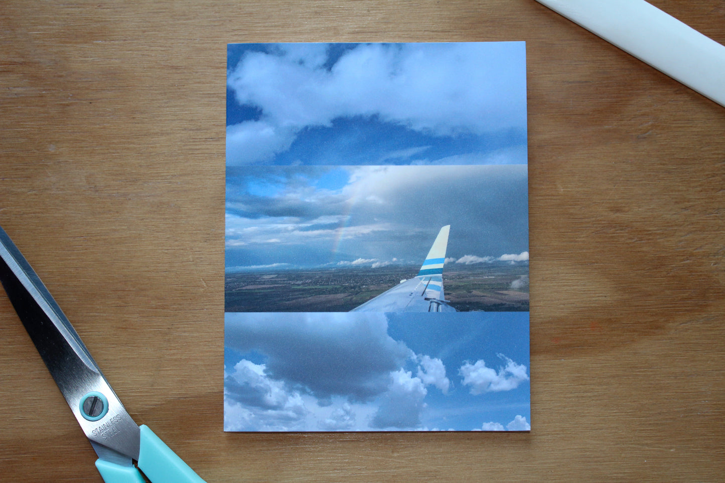 three original photographs that capture the clouds and plane scape and rainbow in the clouds, white and blue hues. scissors and scoring tool on a wood background.