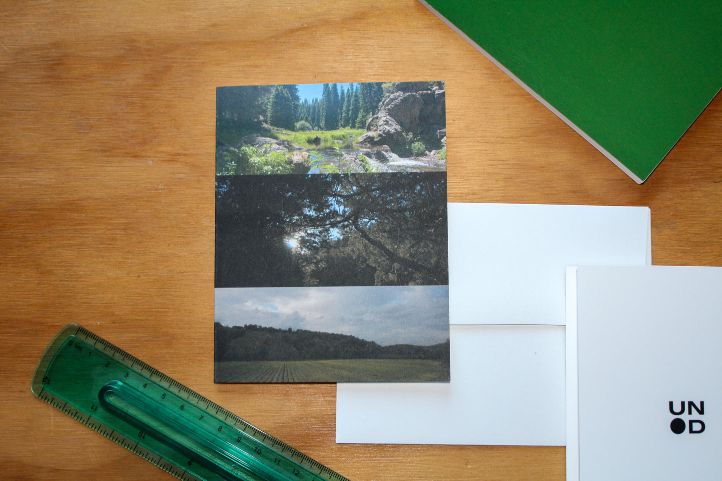 3 photos greenery, showcasing vibrant plants, leaves. wood background, green ruler and green notebook. white envelope and back of the card with the unpunchd logo.