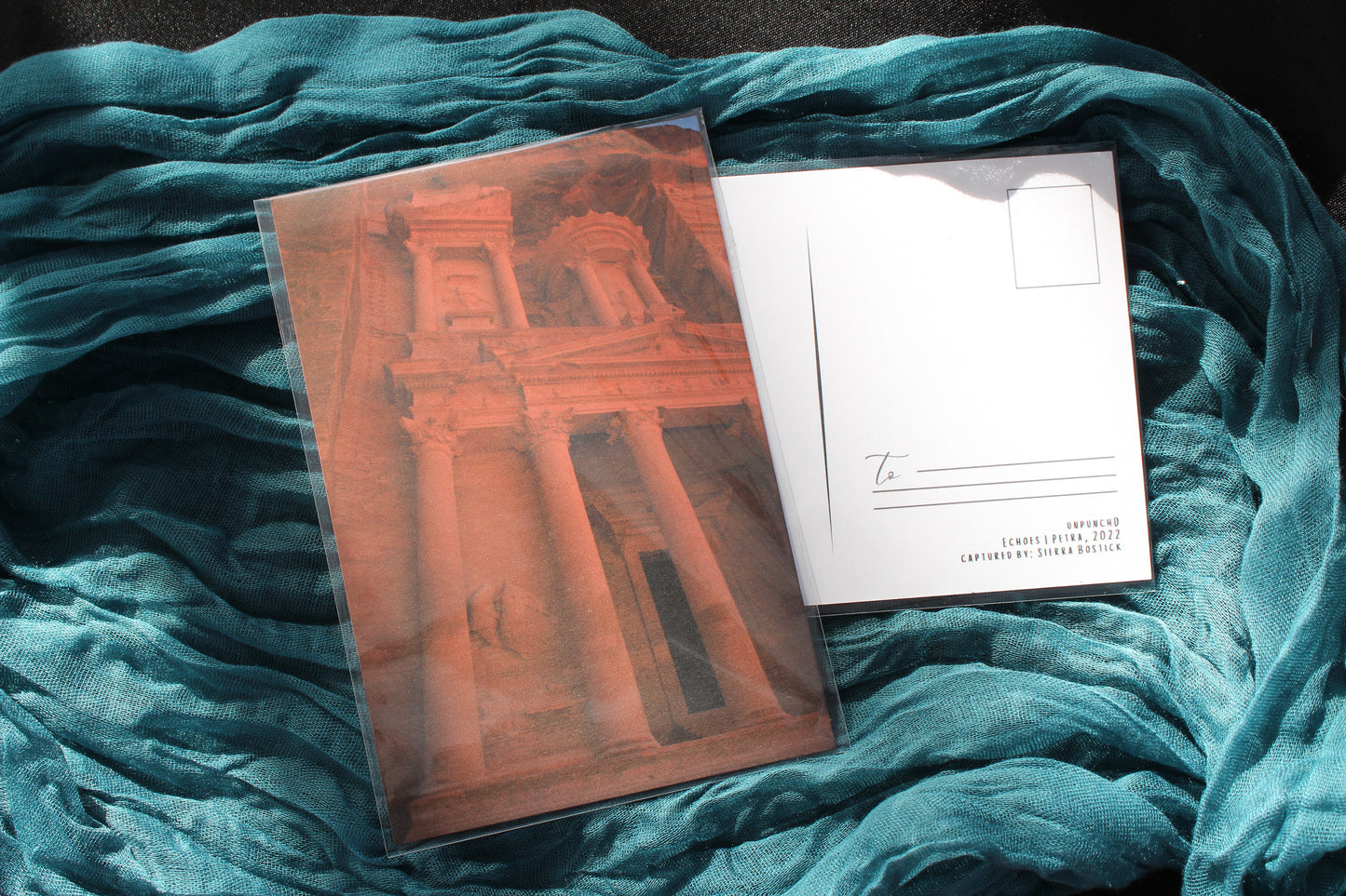 golden hour view of petra, back of the card with to section, unpunchd, title of the photo with the year and captured by listed. Teal and black background.