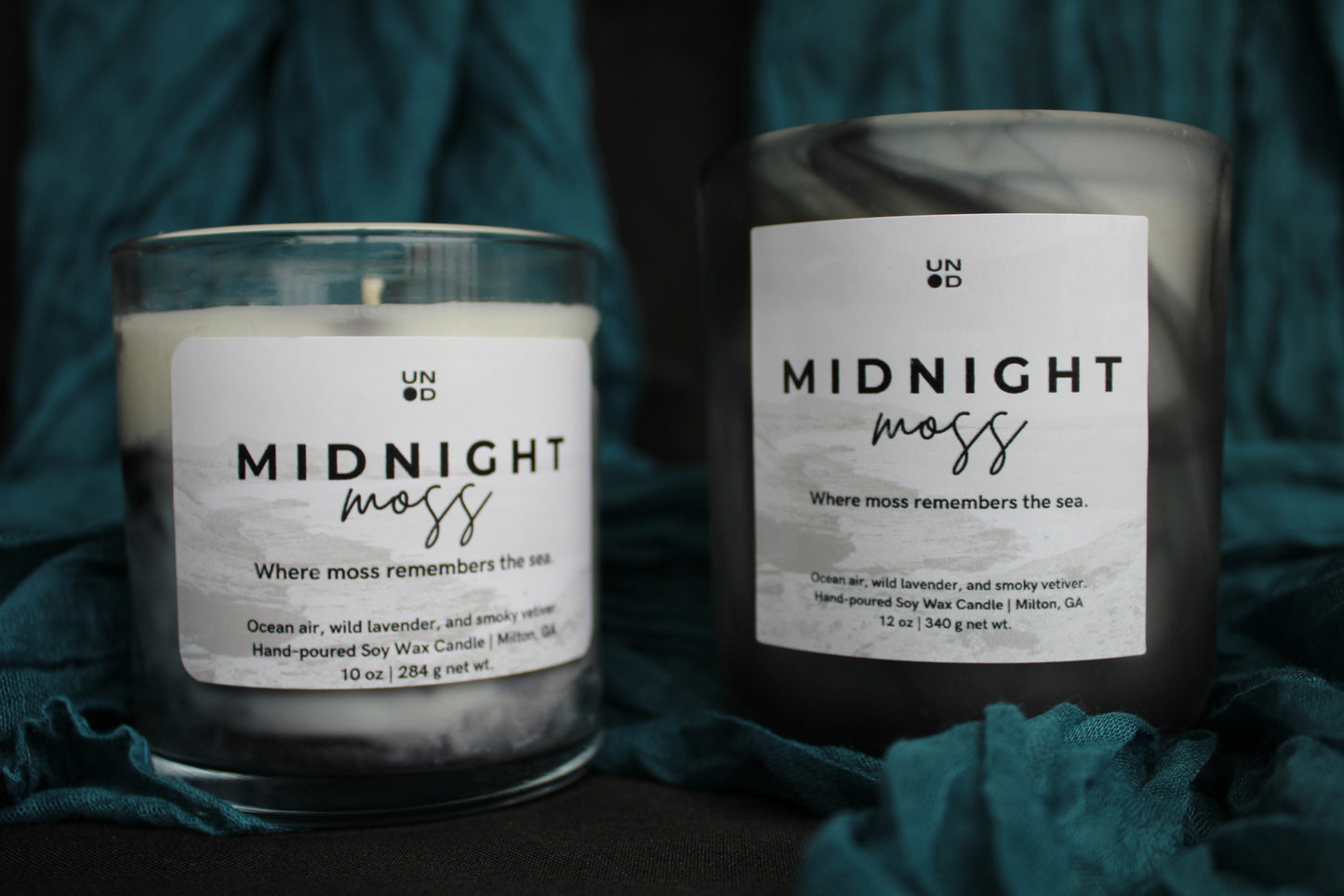 Two candles labeled 'Midnight Moss' on a dark background