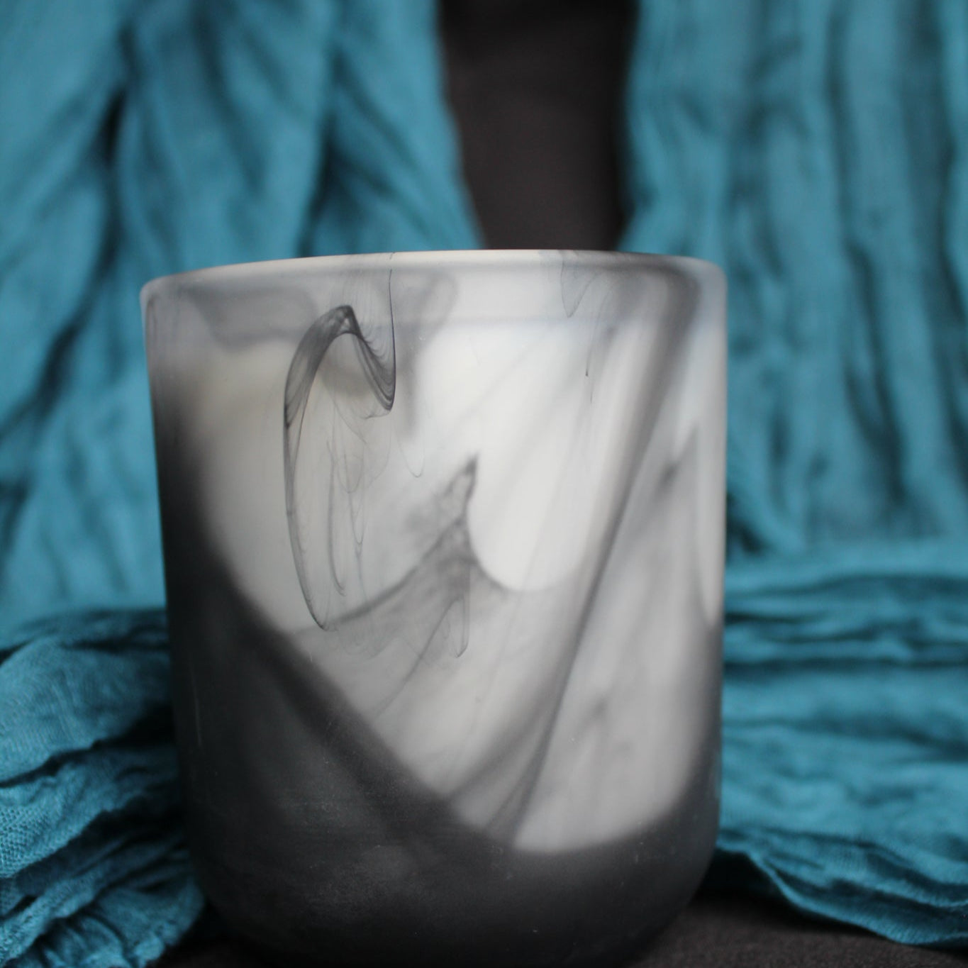 Marble-patterned candle holder on a textured blue fabric background