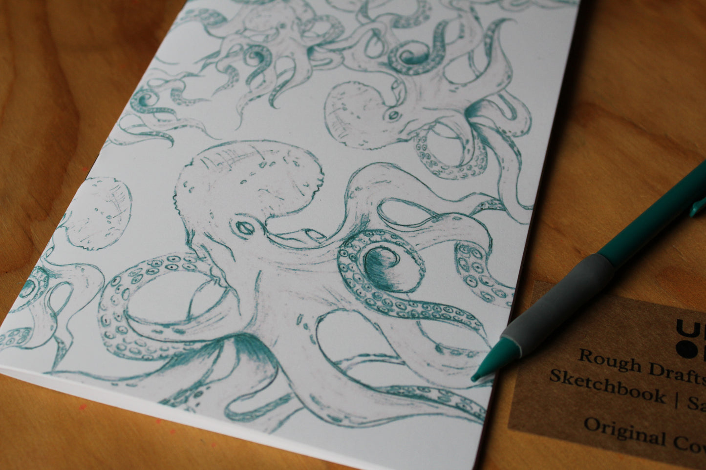 Sheet of paper with octopus drawing and a pen on a wooden surface
