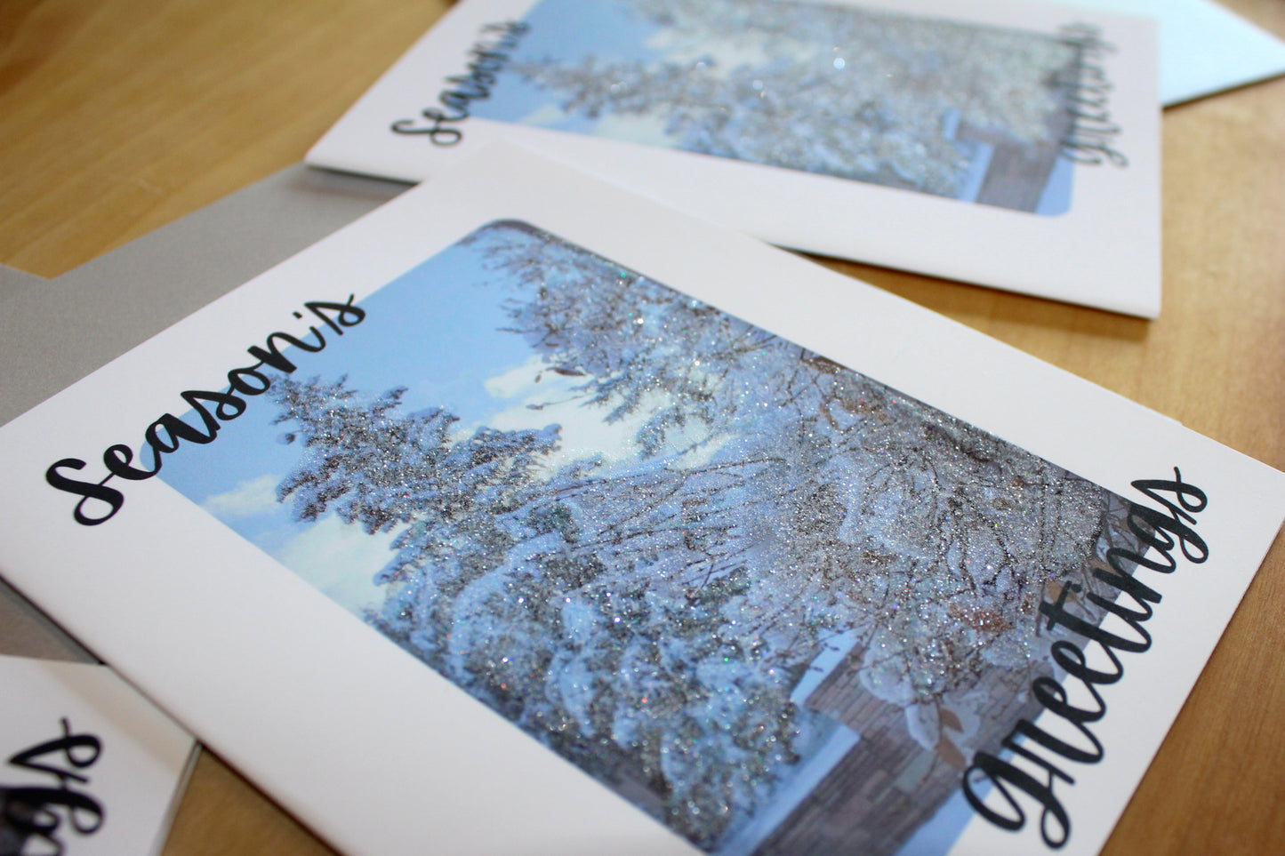 Season's Greetings card with snowy landscape design on a wooden surface