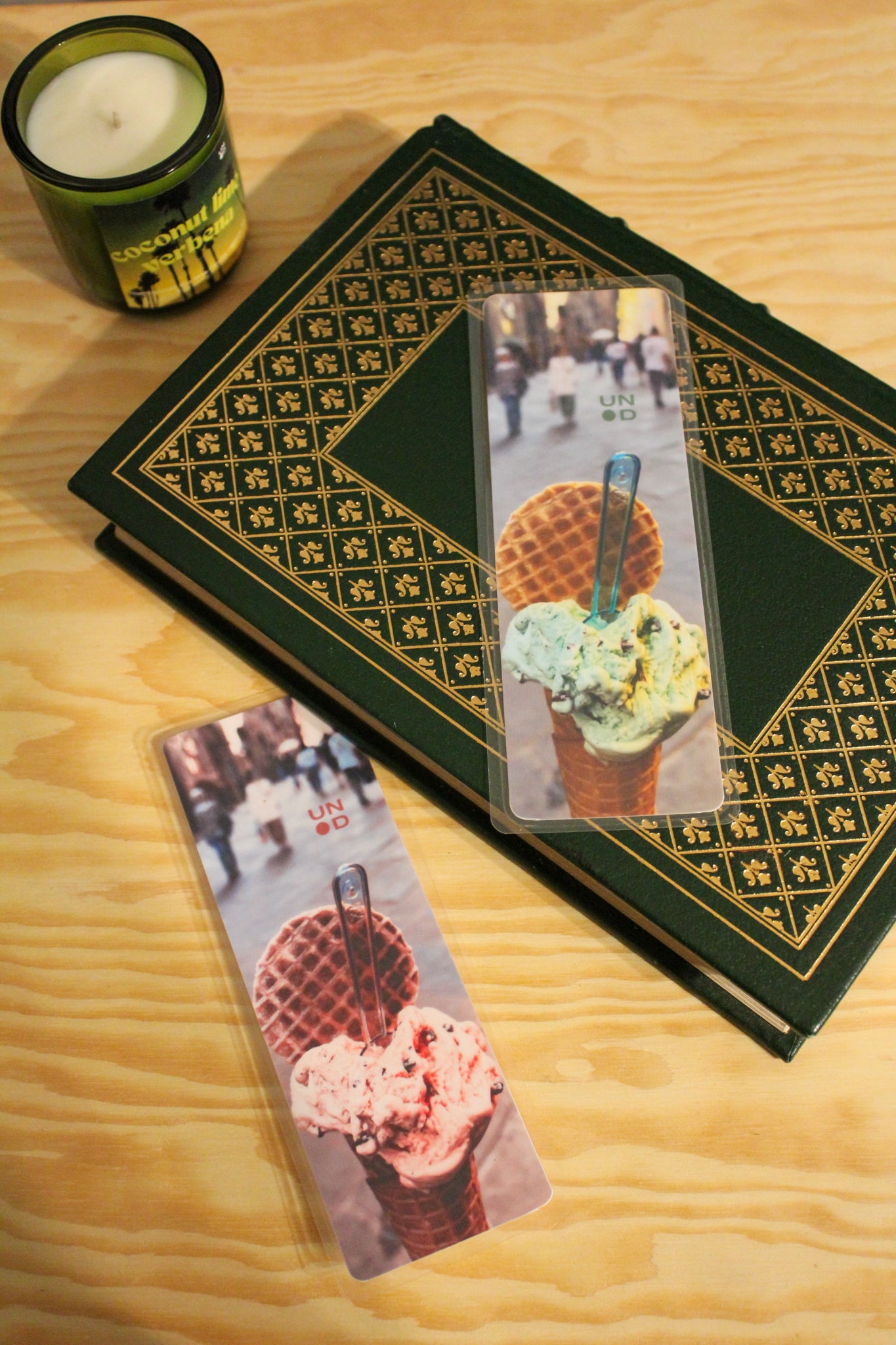 book with decorative cover and bookmarks featuring ice cream images on a wooden surface with a candle