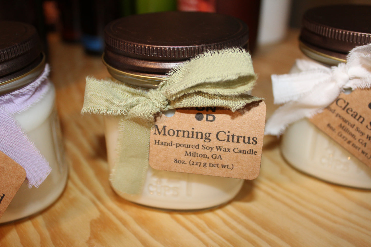 Jar of candle with decorative bow and label on a wooden surface