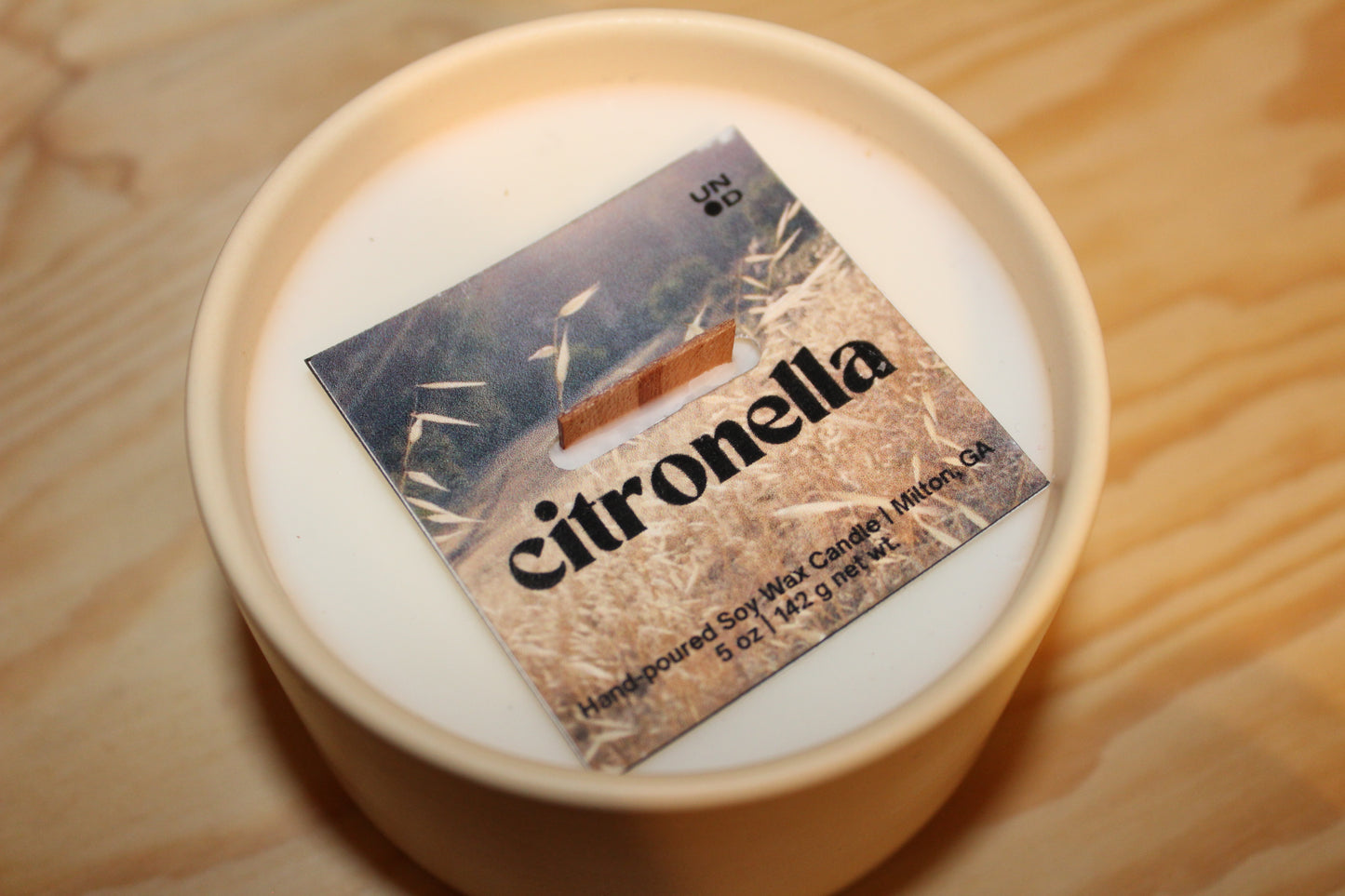 Candle with a 'citronella' label on a wooden surface