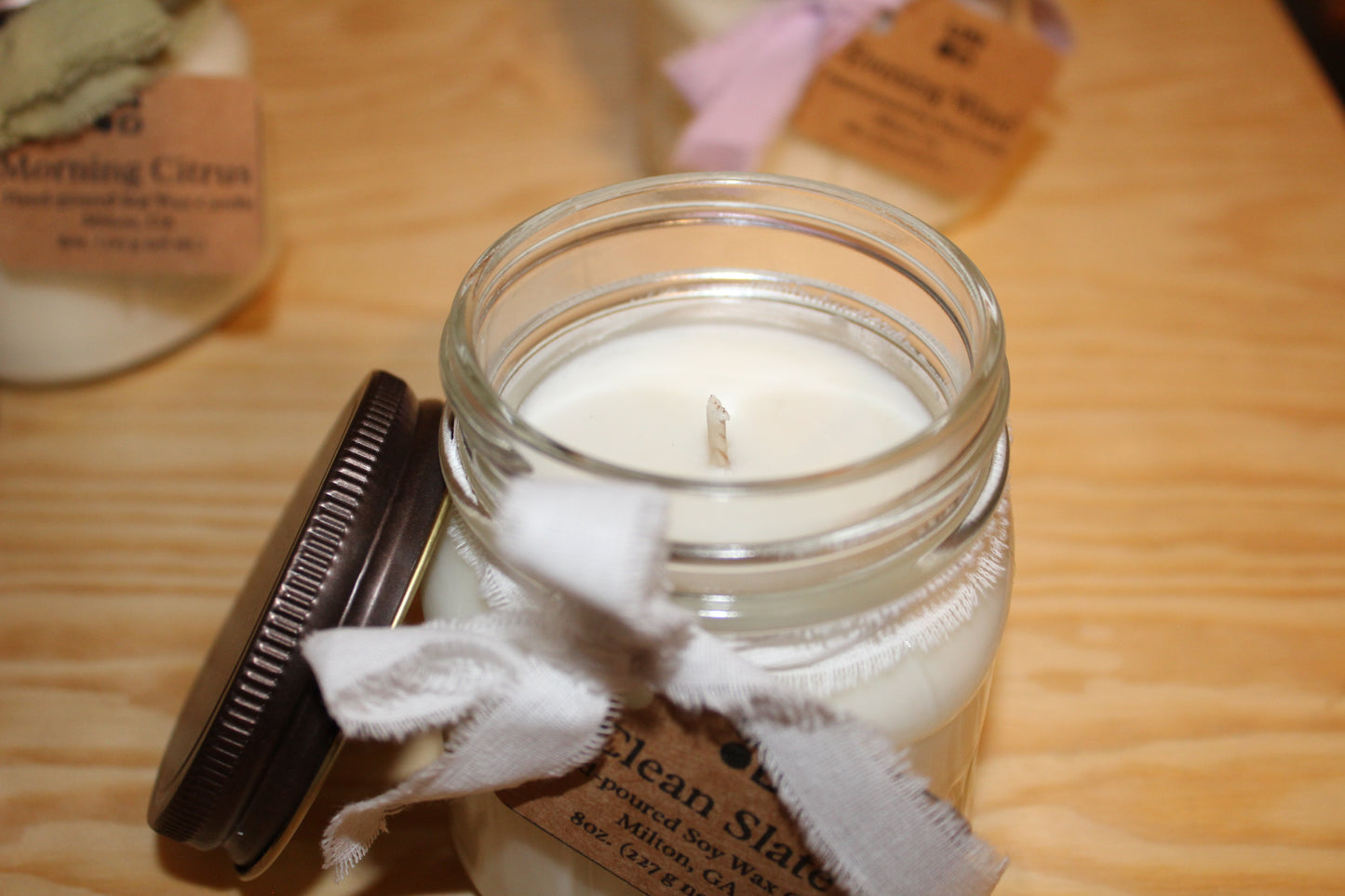 Candle in a glass jar with a label on a wooden surface