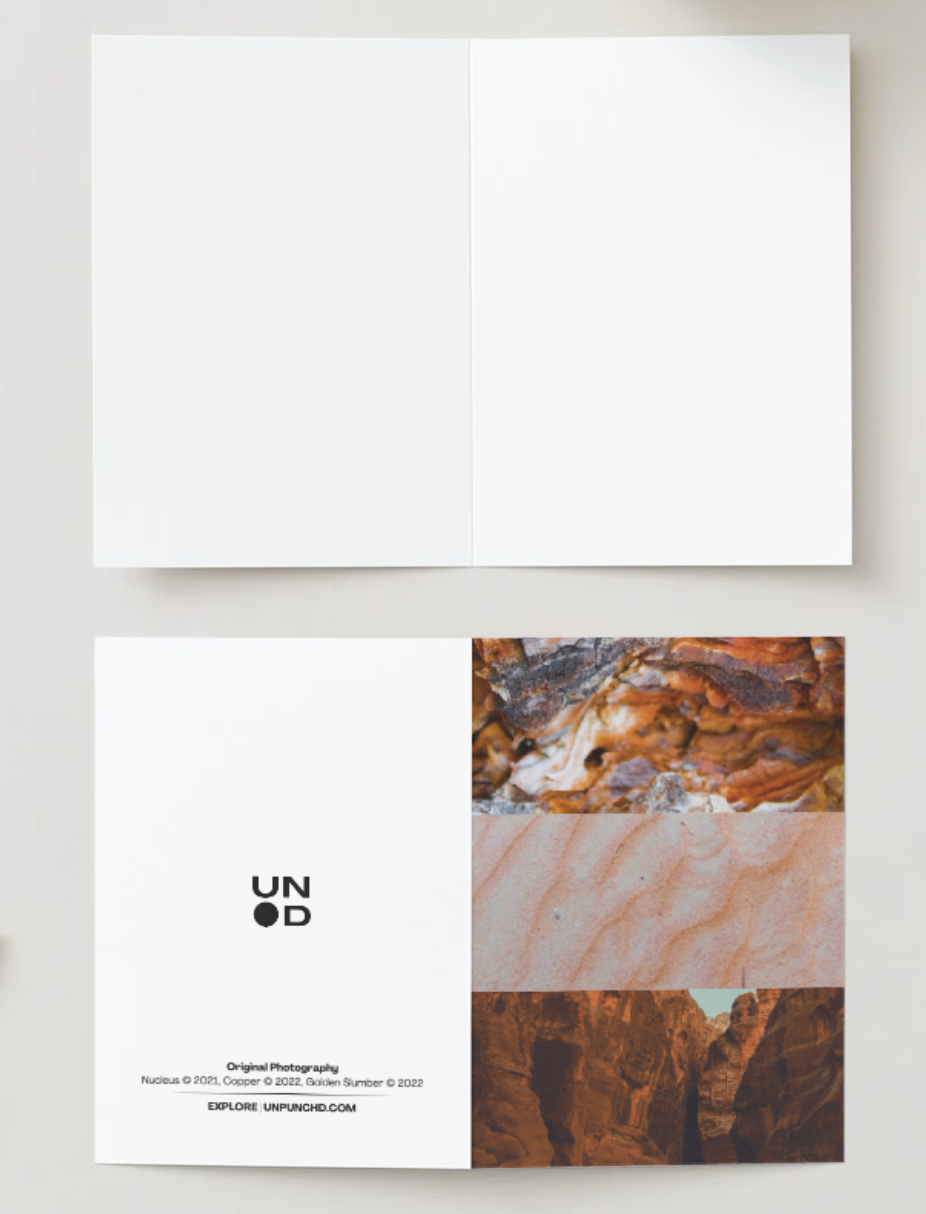 three original photographs that capture the natural beauty of tree bark, sands, and mountains. white card back with logo, photo names and years on an orange notebook white inside card, off-white background