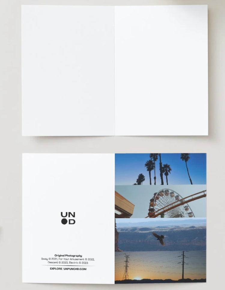 blue monochrome photo card with notebook and blue scissors in the picture - palm trees, ferris wheel, raven, and electric lines
inside of the card - blank on off white background
back of the card - logo and photo names with website