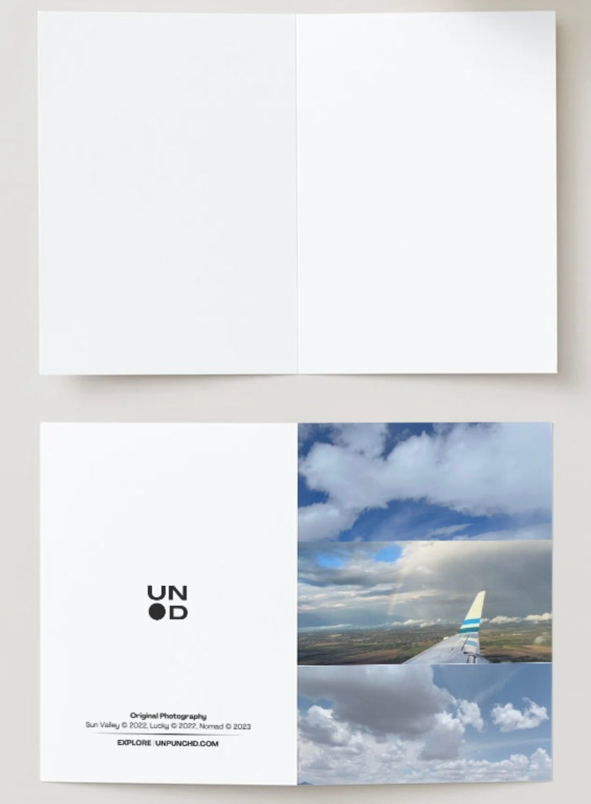 three original photographs that capture the clouds and plane scape and rainbow in the clouds, white and blue hues. back of the card is the unpunchd logo, photography names and years wih the website listed. The inside of the card shown, blank. off-white background.