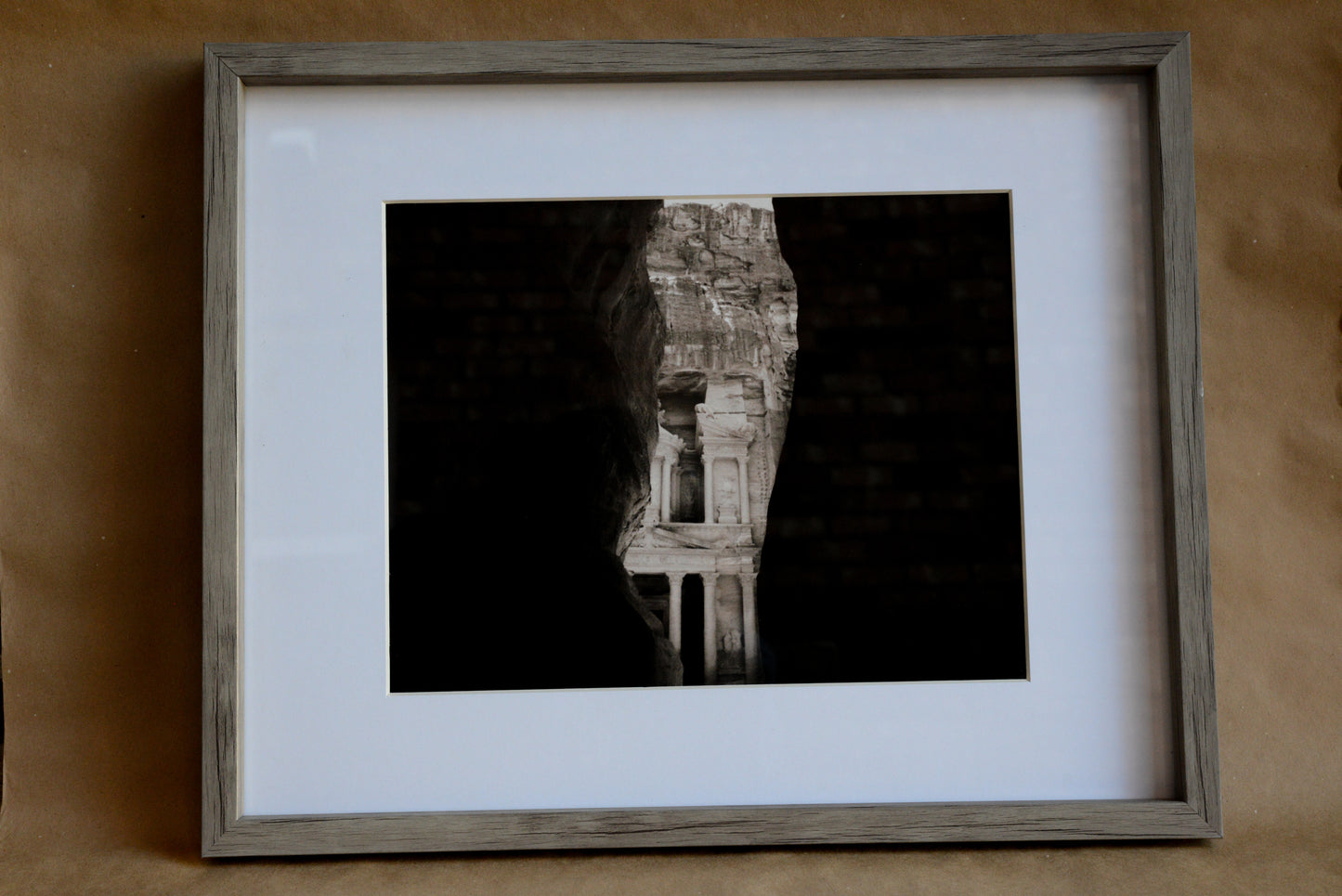 Black and White photo of Petra viewed through Canyon walls. Weathered grey frame, with 2in white matting.