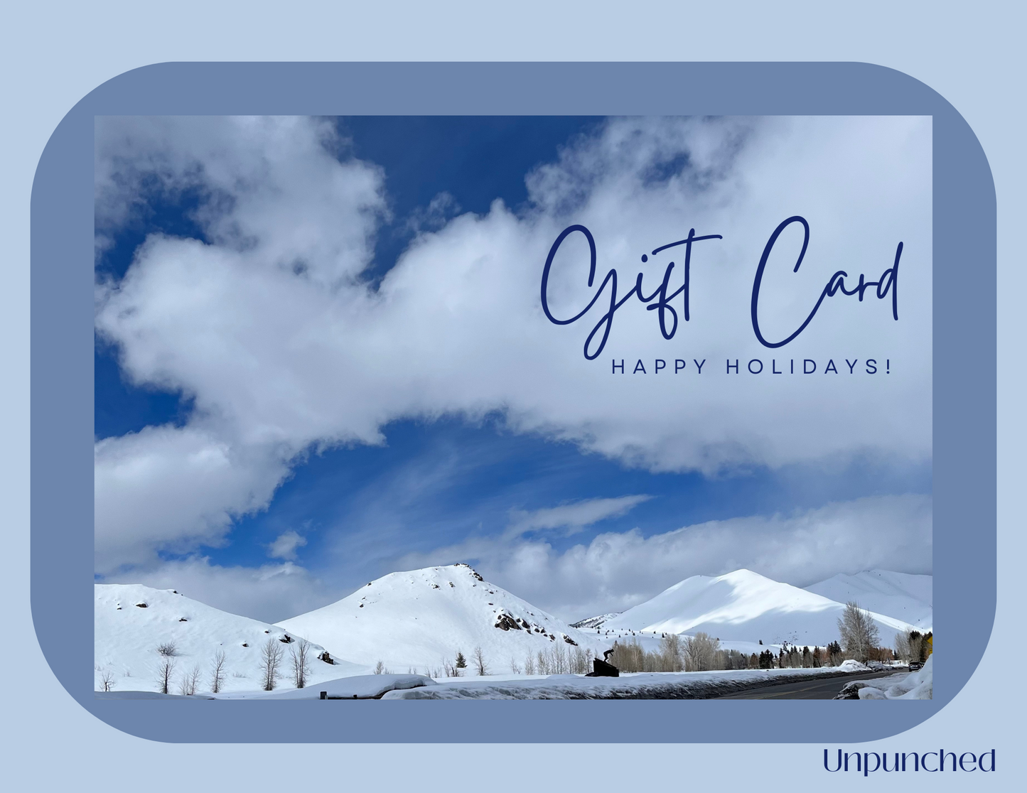 The rectangular background with a car and a photo overlayed of cloudy sky with snow cover mountains on it. The top left reads "Gift Card Happy Holidays!". In the bottom right corner the logo Unpunched is listed on the rectangle. Hues of blue and whites with navy words.