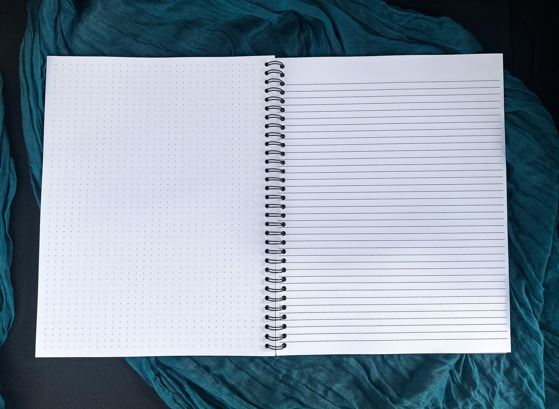 Open notebook with lined and grid pages on a teal fabric background