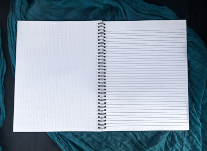 Open notebook with lined and grid pages on a teal fabric background