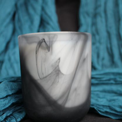 Marble-patterned candle holder on a textured blue fabric background