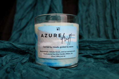 Candle labeled 'Azure Drift' on a textured teal fabric background