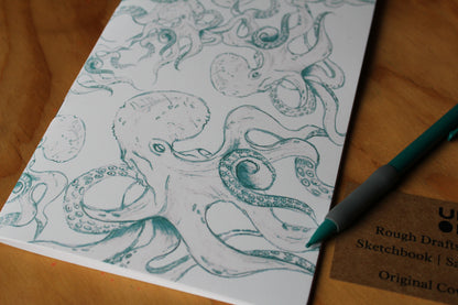 Sheet of paper with octopus drawing and a pen on a wooden surface