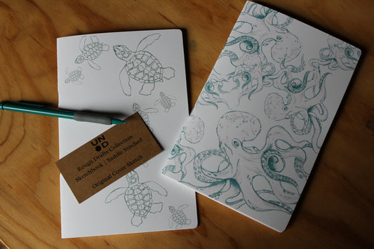 Two notebooks with turtle and octopus illustrations on a wooden surface