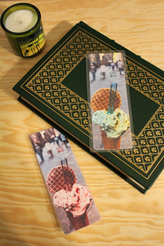 book with decorative cover and bookmarks featuring ice cream images on a wooden surface with a candle