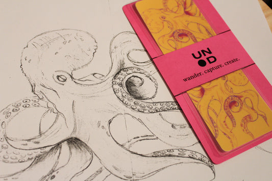 Pink bell band with yellow bookmark next to a black and white octopus illustration.