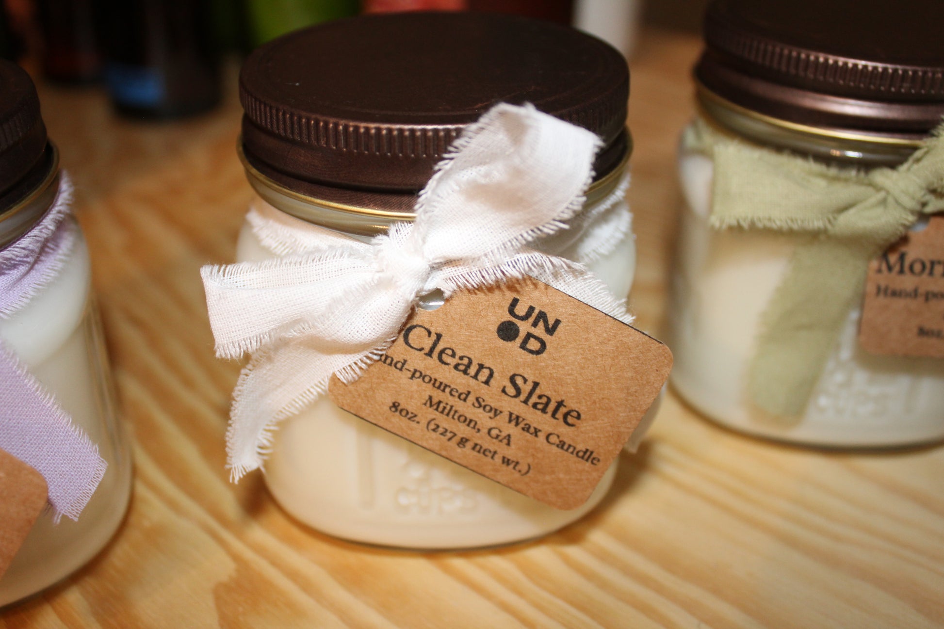 Jar of candle with a decorative bow and label on a wooden surface