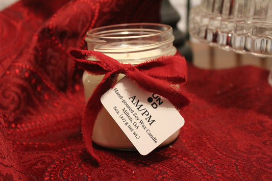Small jar with a red bow and AM/PM label on a red textured surface