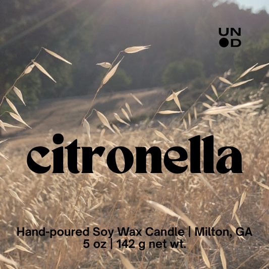 Hand-poured soy wax candle with 'citronella' text and Unpunchd logo on a natural background.