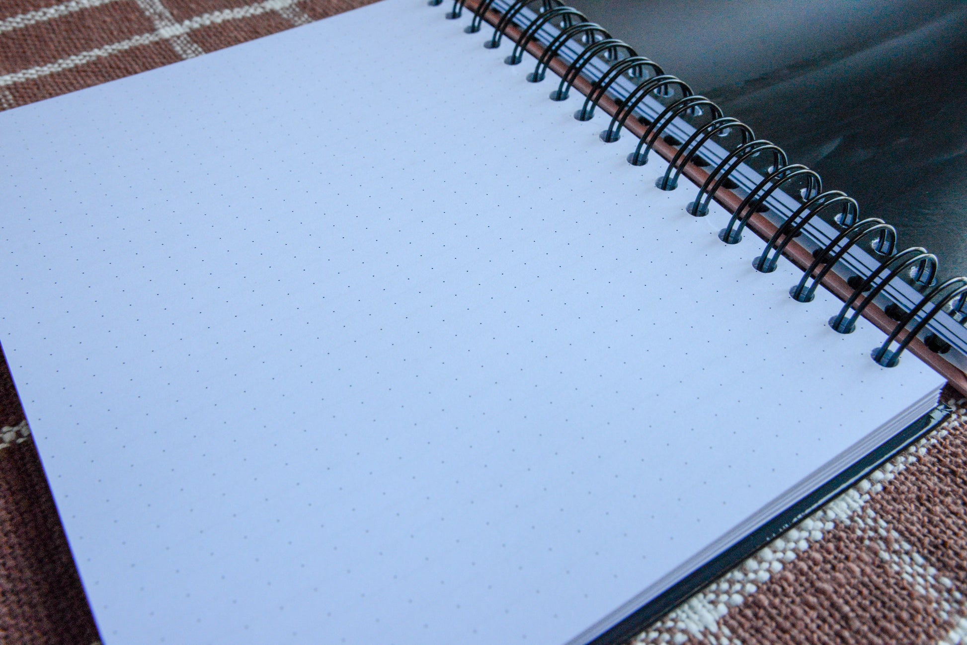 spiral notebook with dot grid page in view. image of haze partial greyscale image. 